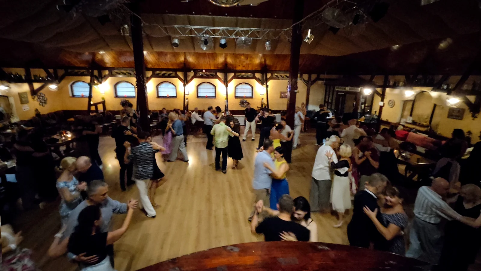 Пари танцюють на мілонзі у великому залі La isla de Tango